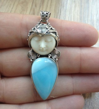 Zilveren hanger met gezicht uit been gesneden en Larimar druppel
